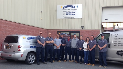Team of Enhanced Heating and Air Conditioning professionals in front of their service vehicles and company sign, showcasing HVAC expertise in Elkton, MD.