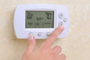 Thermostat being adjusted, displaying settings of 68°F and 70°F, relevant for air conditioning inspection and maintenance guidance.