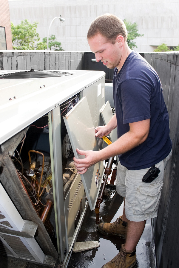 Technician performing maintenance on an air conditioning unit, inspecting internal components to ensure optimal performance and energy efficiency.