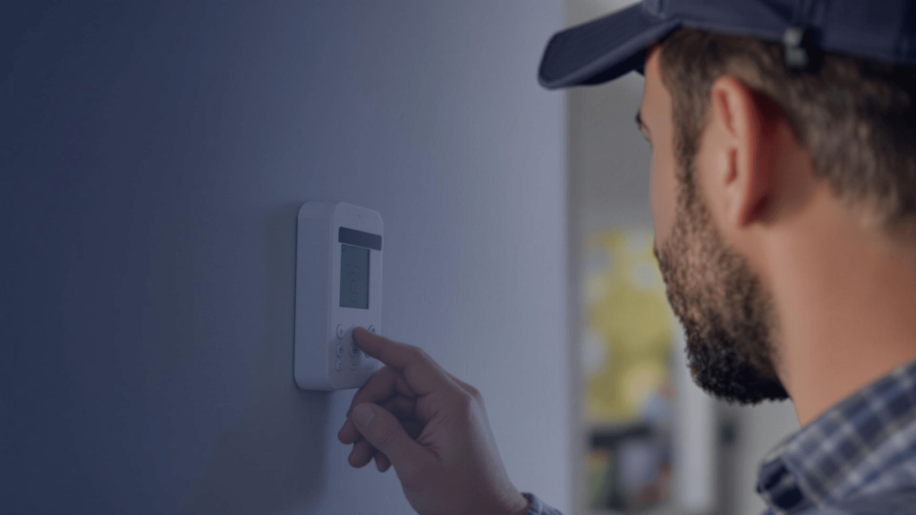 Technician adjusting a digital thermostat on a wall, emphasizing HVAC repair and replacement services in Newark, Delaware.
