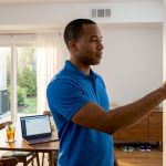 Homeowner adjusting central air control in dining room